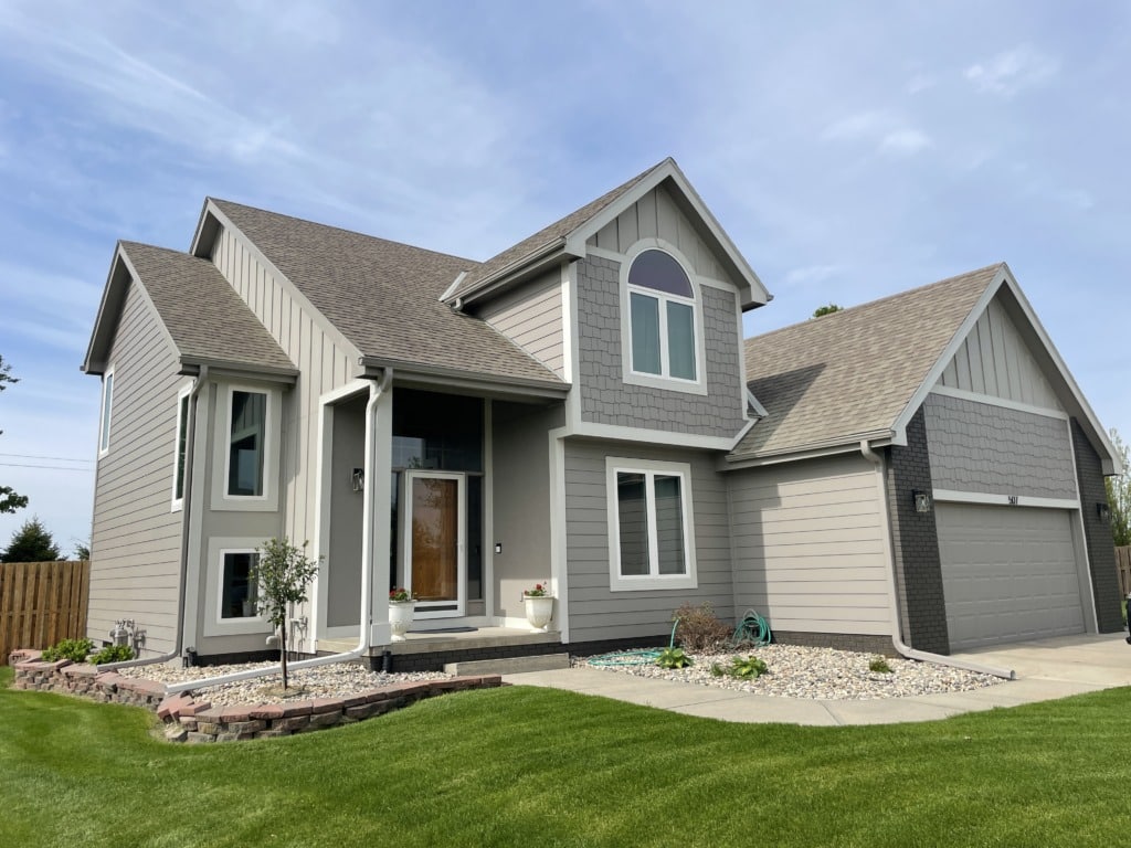 Brown home with James Hardie shakes in the gables, board and batten accents over garage